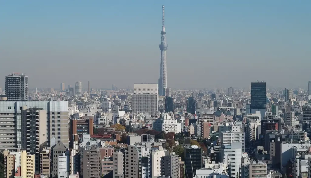 Panorama da cidade de Tóquio com a Tokyo Skytree dominando o horizonte sob um céu azul claro."