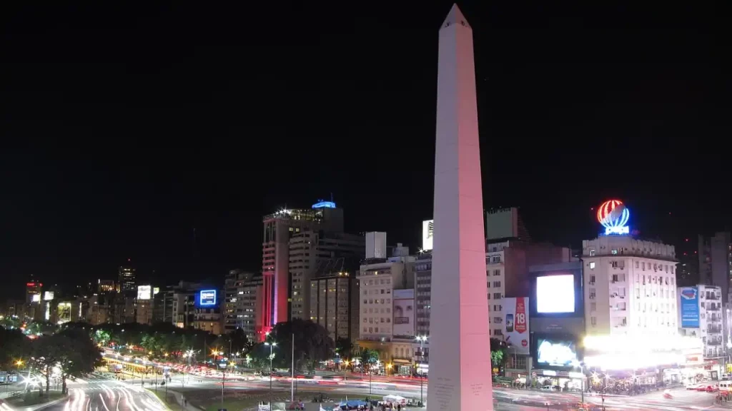 Vista noturna do Obelisco em Buenos Aires, Argentina, com ruas iluminadas e prédios ao fundo