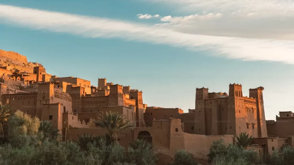 Vista de construções tradicionais de barro em Ait Benhaddou, Marrocos, com céu azul e poucas nuvens ao fundo