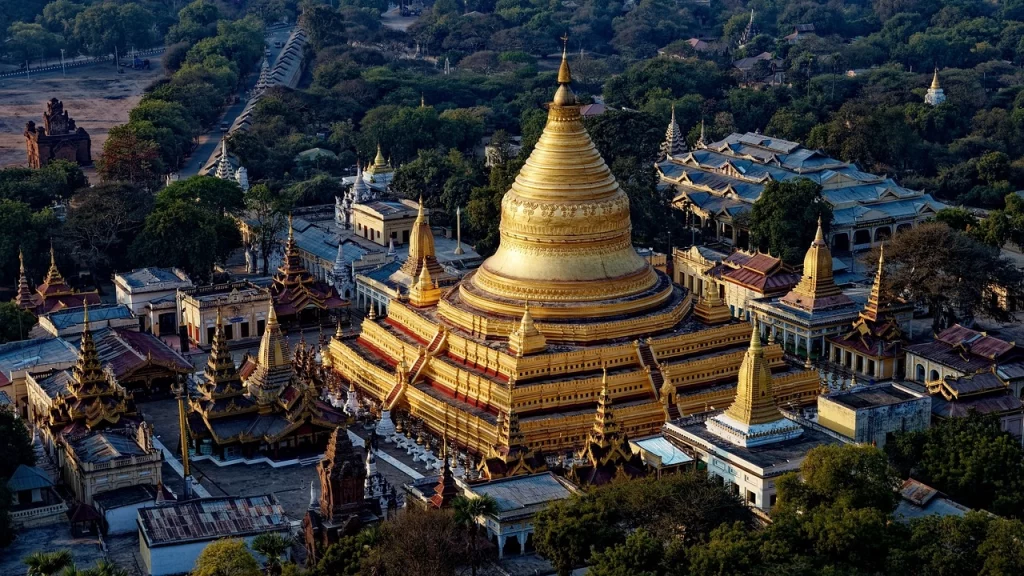 Templos dourados de Bagan, Myanmar, vistos de cima ao entardecer, cercados por vegetação densa e paisagens históricas