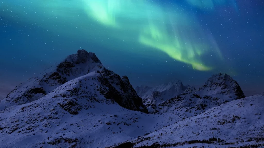 A deslumbrante aurora boreal verde dançando no céu sobre montanhas cobertas de neve, criando um cenário mágico e surreal.