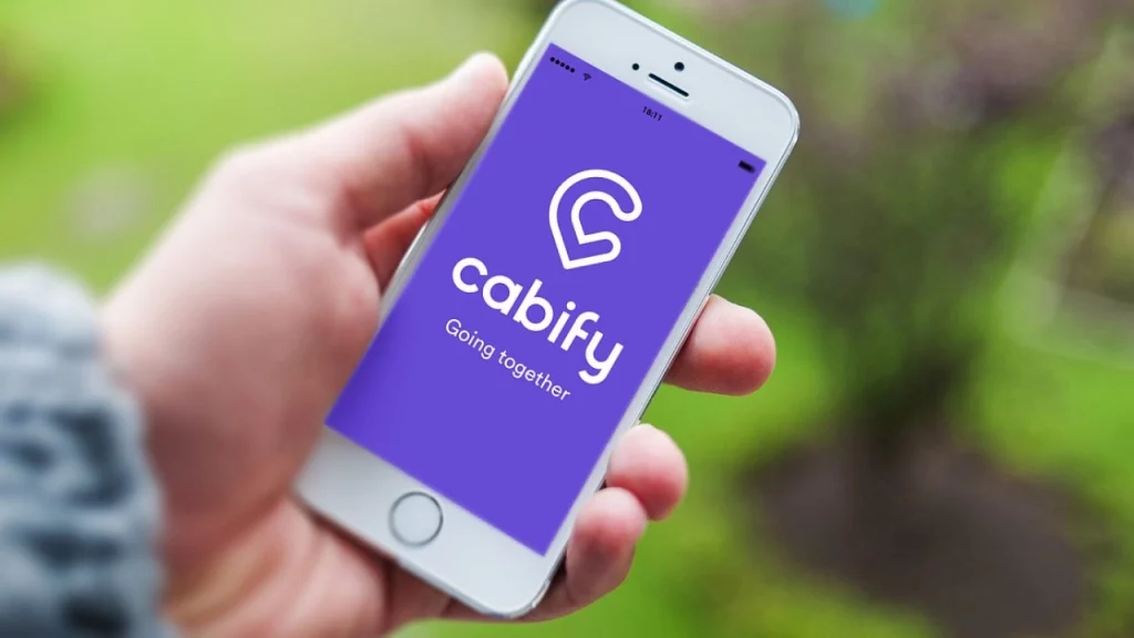 Tela de um smartphone com o aplicativo Cabify aberto, enquanto uma pessoa segura o celular ao ar livre.