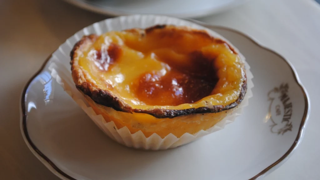 Close de um pastel de nata, doce tradicional português, servido em um prato no Café Majestic, no Porto.