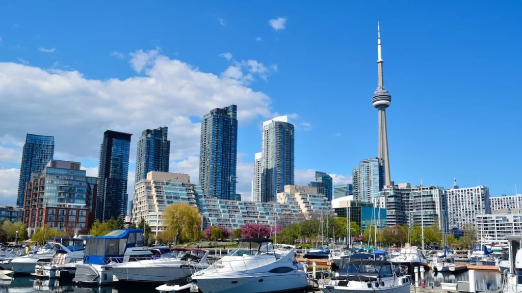 Skyline de Toronto com a CN Tower em destaque, visto a partir do porto, com iates e barcos atracados em um dia ensolarado.