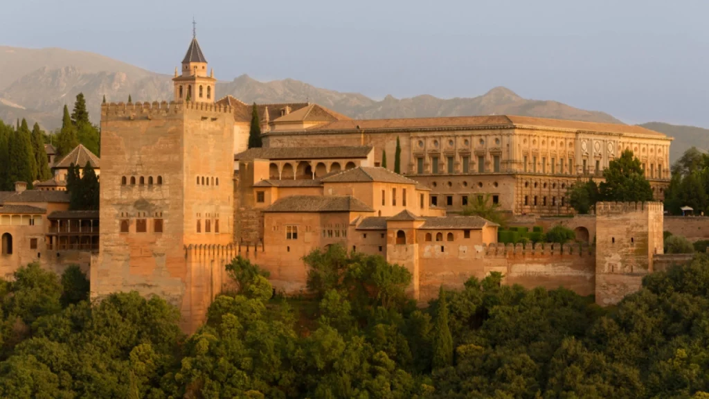 Vista da Alhambra ao entardecer em Granada, com a paisagem montanhosa ao fundo.