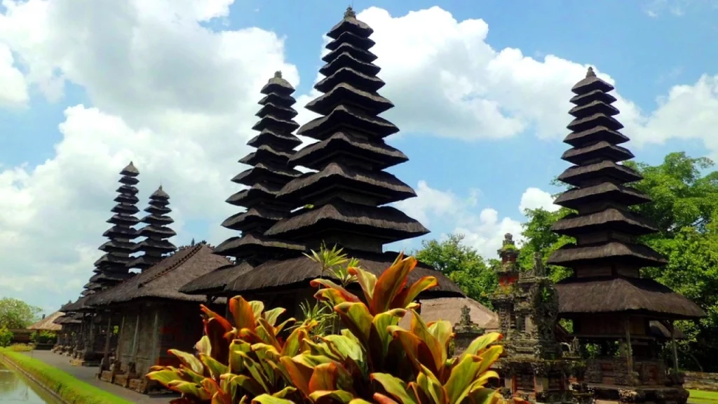 emplo tradicional na Indonésia com várias torres de telhado escalonado, cercado por vegetação exuberante e céu azul.