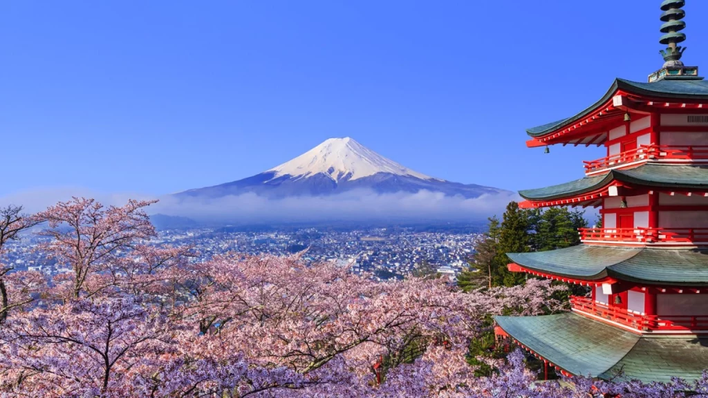 Vista do Monte Fuji no Japão, com cerejeiras em flor e uma tradicional pagoda vermelha em primeiro plano.