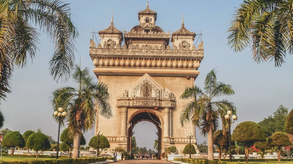 Patuxai, o Arco do Triunfo de Vientiane, no Laos, cercado por palmeiras e jardins.