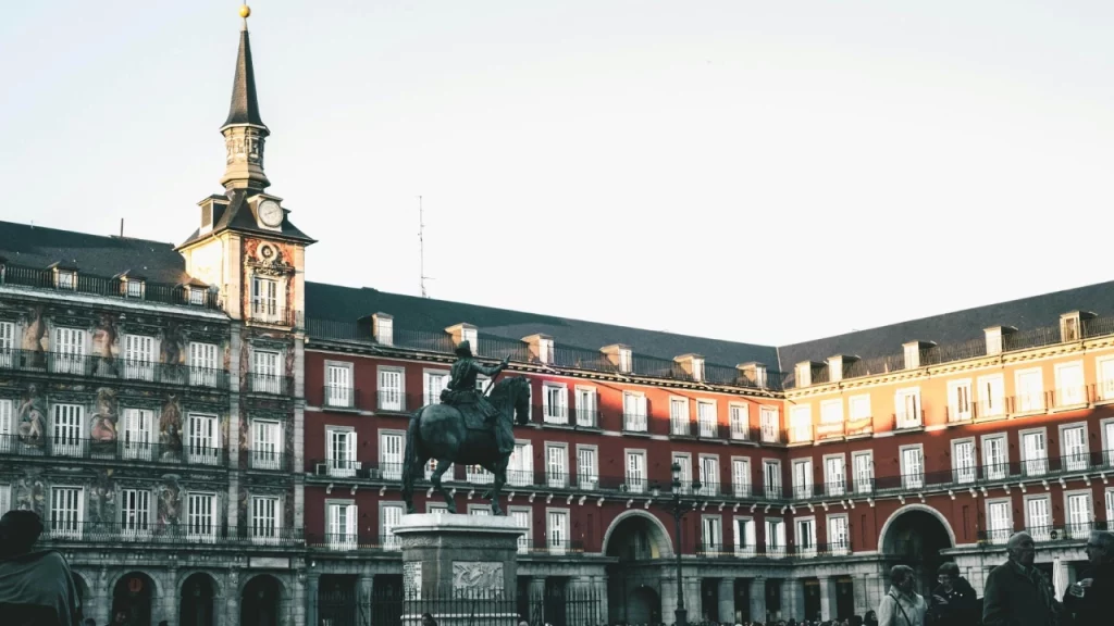 Praça Mayor em Madri ao pôr do sol, com sua arquitetura imponente e estátua equestre no centro.