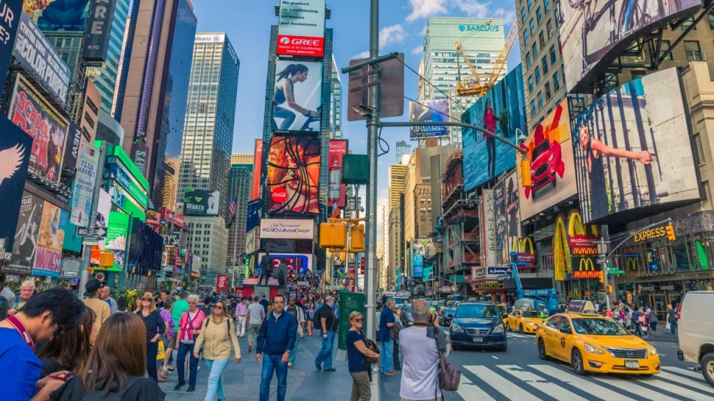 A movimentada Times Square em Nova York, cheia de letreiros coloridos e multidões de turistas passeando pelas ruas.