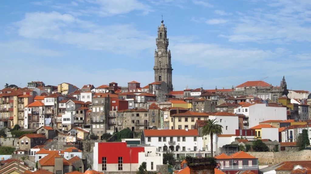 Vista panorâmica da cidade do Porto, Portugal, com a Torre dos Clérigos em destaque e casas com telhados tradicionais ao redor.