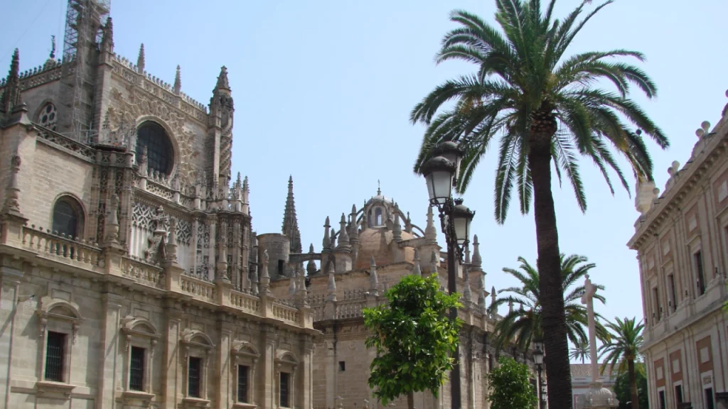 Catedral de Sevilha cercada por palmeiras e arquitetura histórica, um exemplo da beleza da cidade.