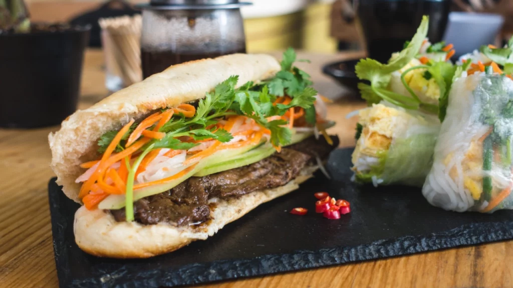 Close-up de um banh mi vietnamita e rolinhos primavera frescos, destacando os sabores autênticos da gastronomia local.