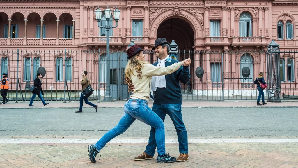 Casal dançando tango em frente à emblemática Casa Rosada, em Buenos Aires, celebrando a cultura e o charme argentino