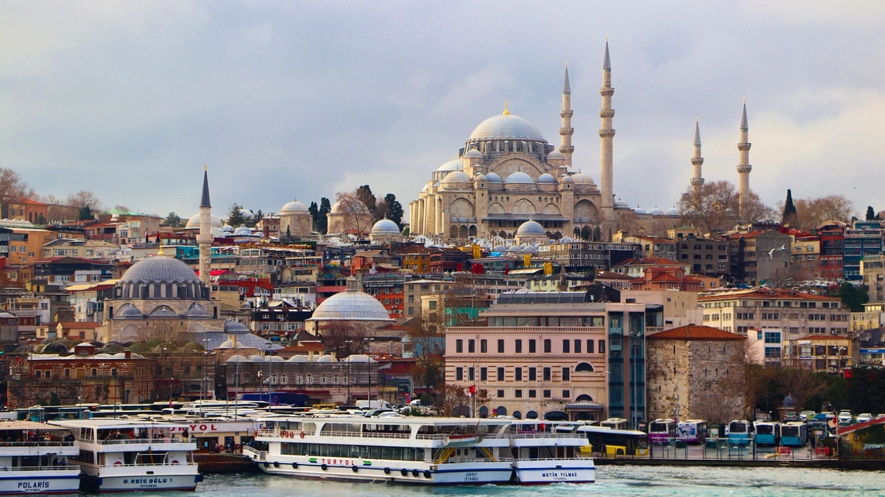 Vista panorâmica de Istambul com a impressionante Mesquita Süleymaniye ao fundo, cercada pelas coloridas construções da cidade e barcos navegando pelo Bósforo.