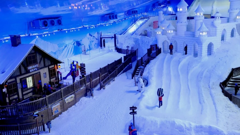 Parque Snowland em Gramado, um parque de neve indoor com castelos de gelo, escorregadores e chalés temáticos, onde visitantes se divertem na neve artificial.