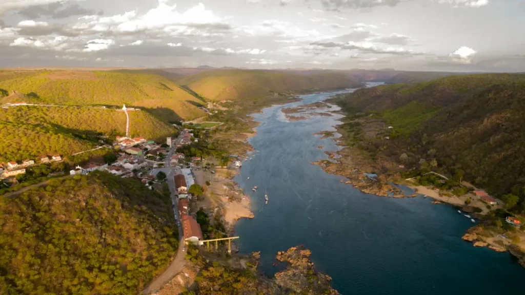 Vista aérea do Rio São Francisco e das serras ao redor, ilustrando a paisagem típica de Piranhas, no sertão alagoano.