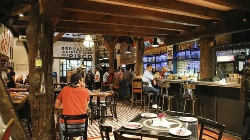 Interior do restaurante Chipe Libre em Santiago, com ambiente rústico, balcão iluminado e placas que destacam a “República Independiente del Pisco"