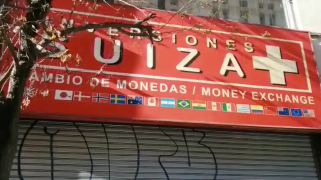 Fachada da casa de câmbio Inversiones Suiza em Santiago, Chile, com letreiro vermelho, bandeiras internacionais e símbolo de cruz suíça.