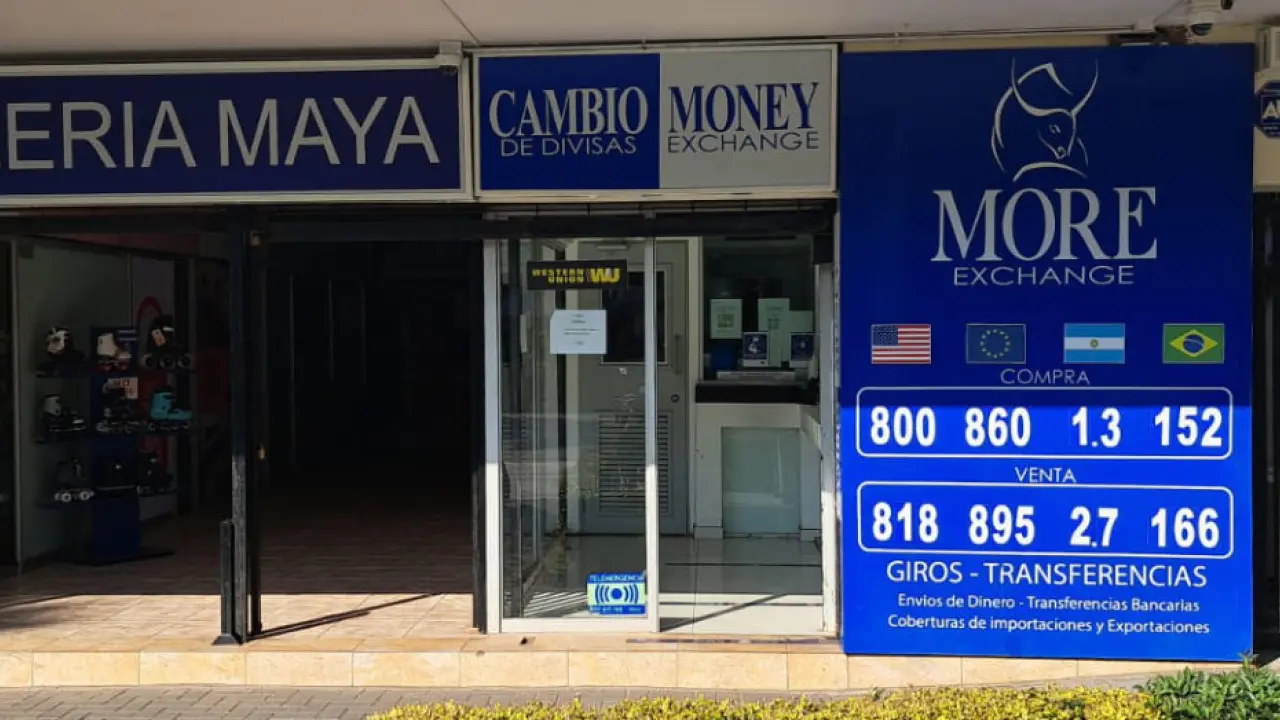 Entrada da casa de câmbio More Exchange em Santiago, Chile, com painel azul exibindo as cotações e bandeiras de diferentes países.