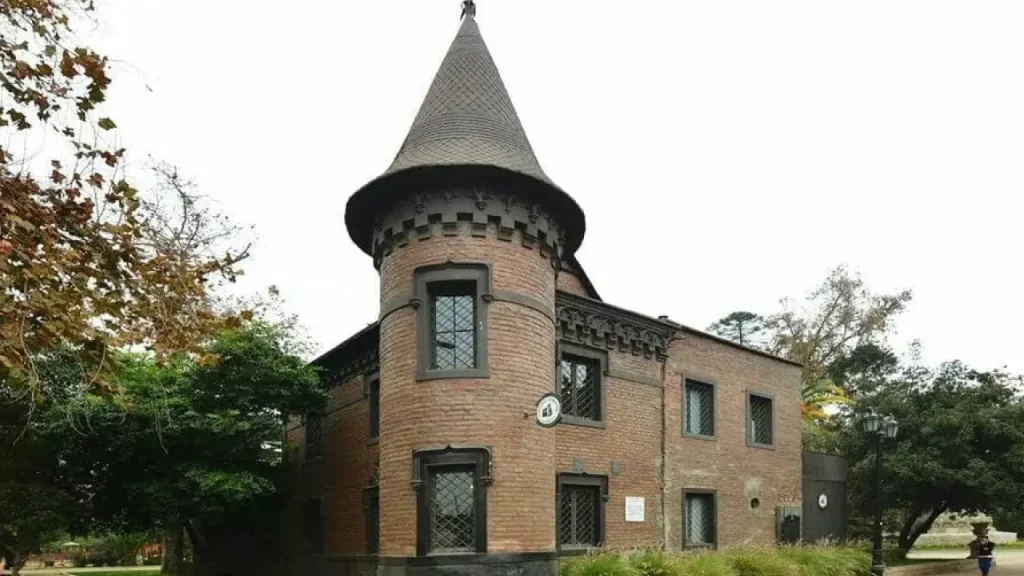 Prédio histórico de tijolos vermelhos com torre em formato de castelo, onde funciona o restaurante Castillo Forestal, em meio ao Parque Forestal de Santiago.