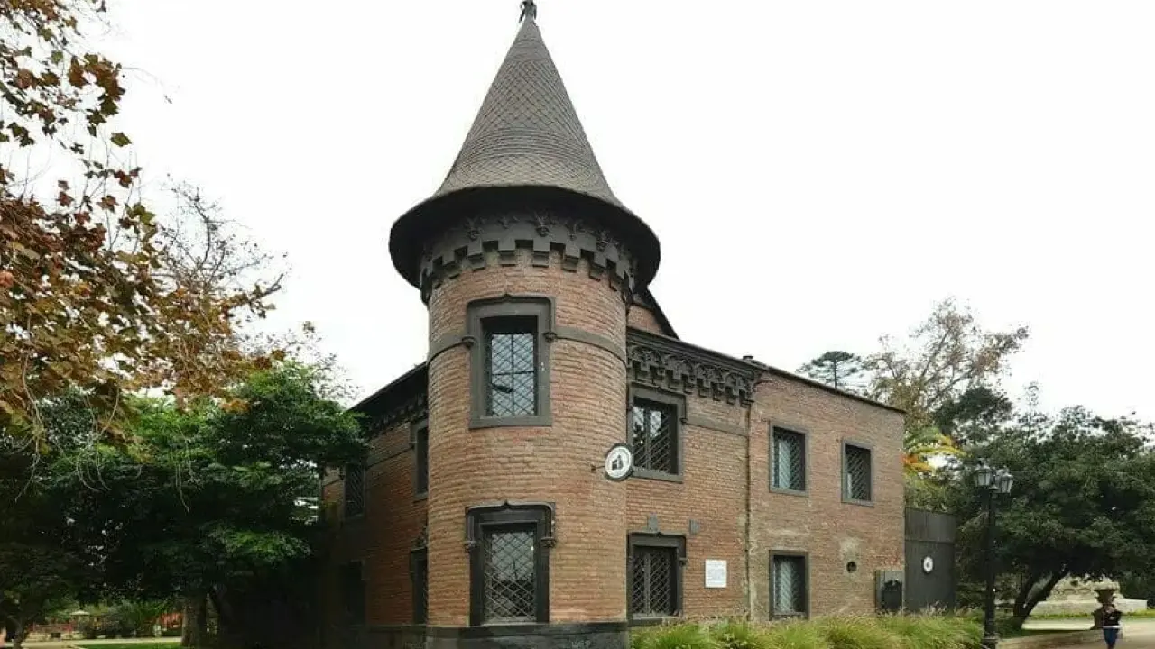 Prédio histórico de tijolos vermelhos com torre em formato de castelo, onde funciona o restaurante Castillo Forestal, em meio ao Parque Forestal de Santiago.