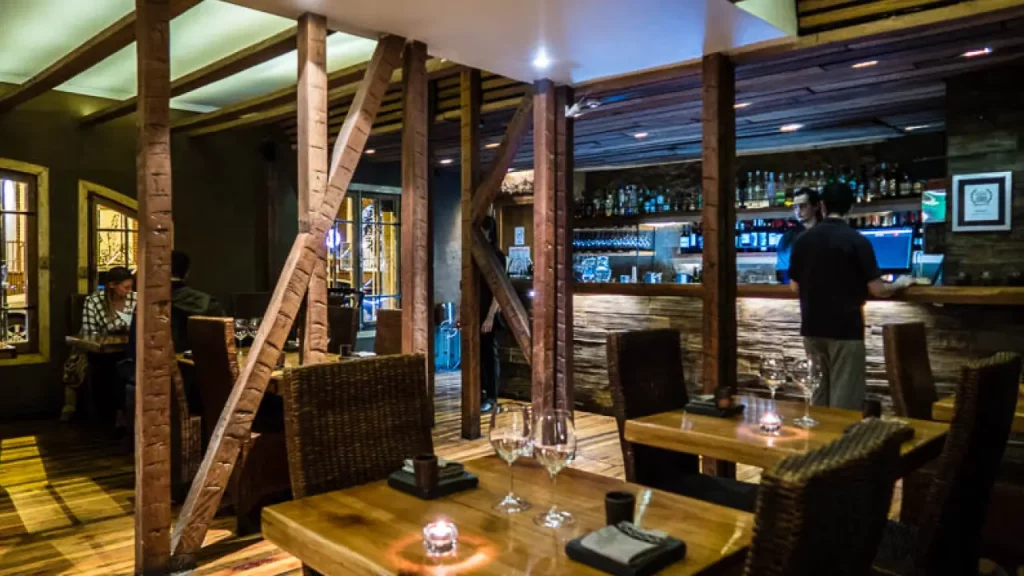 Interior do restaurante Peumayén Ancestral Food em Santiago, com iluminação aconchegante, mesas de madeira, decoração rústica e ambiente ideal para um jantar intimista.