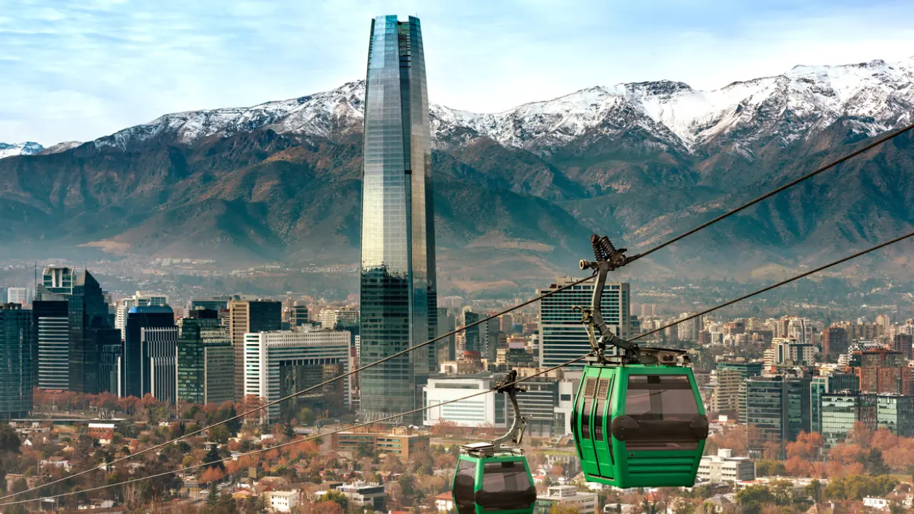 Vista panorâmica de Santiago com o edifício Sky Costanera, o teleférico e a Cordilheira dos Andes ao fundo.