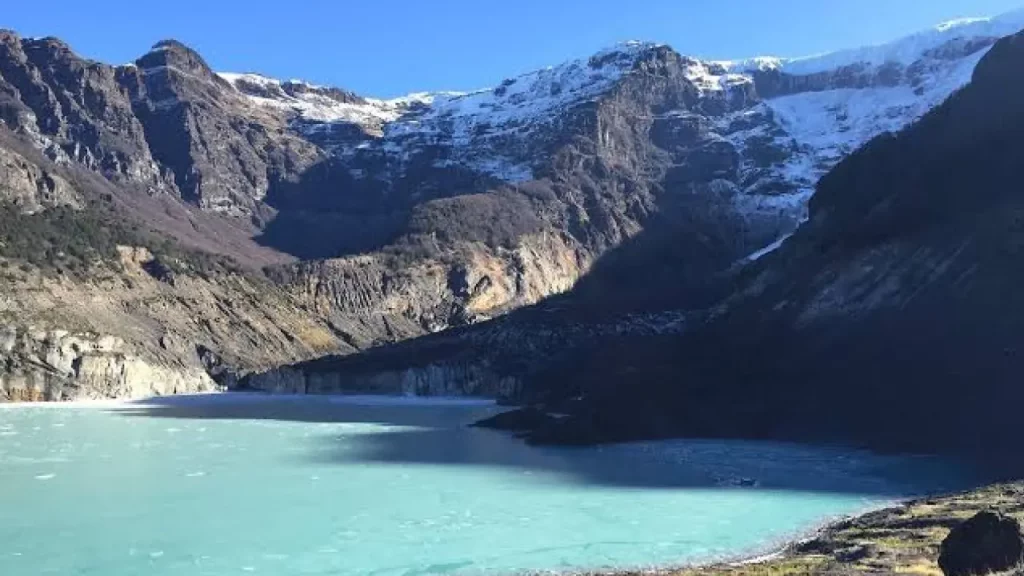 Lago glaciar de águas azul-turquesa aos pés do Cerro Tronador, com montanhas nevadas ao fundo.