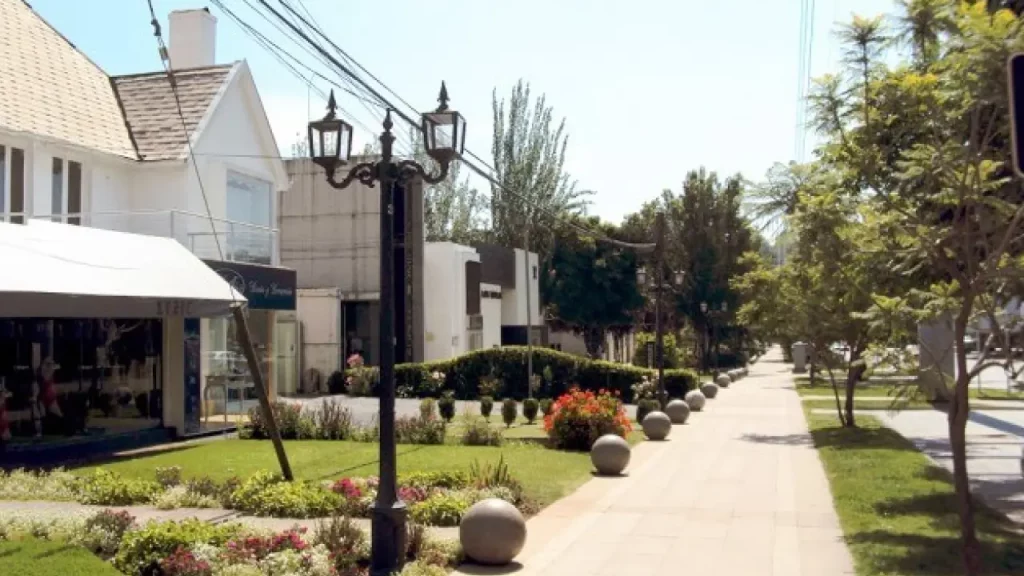 Rua elegante e tranquila em Vitacura, Santiago, com lojas de alto padrão, jardins bem cuidados e calçadas amplas.