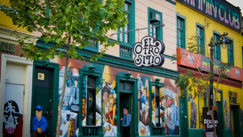 Rua colorida no bairro Bellavista em Santiago com bares e arte urbana nas fachadas, destacando a vida noturna e boêmia da região.