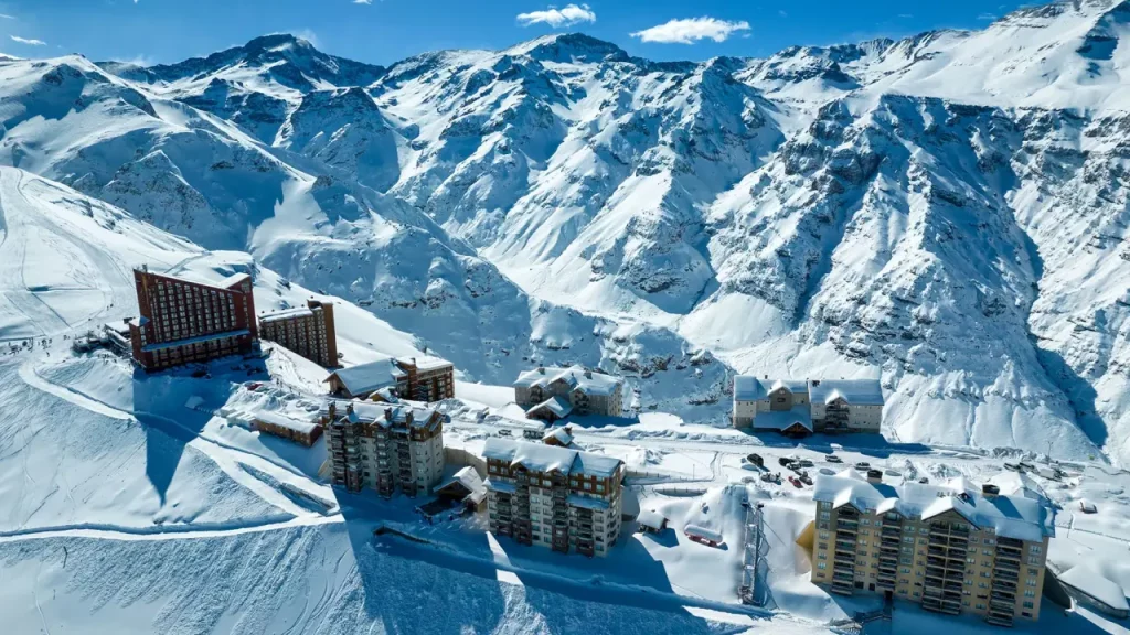 Vista aérea da estação de esqui Valle Nevado no Chile cercada por montanhas cobertas de neve.