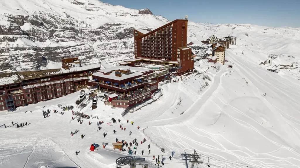 Estação de esqui Valle Nevado coberta de neve, com turistas esquiando e hotéis integrados à paisagem da Cordilheira dos Andes.