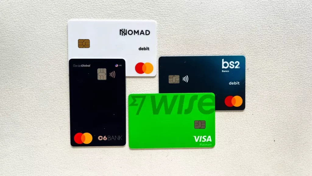Cartões de crédito internacionais Wise, Nomad, C6 Bank e BS2 sobre fundo claro