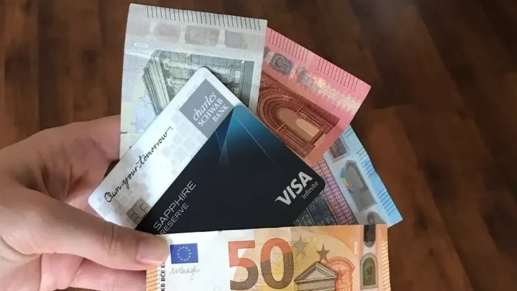 Pessoa segurando cartões e notas de euro, simulando viagem internacional