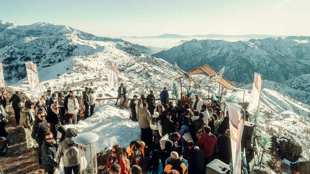 Festa ao ar livre durante o pôr do sol na neve em Farellones, com vista para a Cordilheira dos Andes e público reunido no Zerando Sunset.