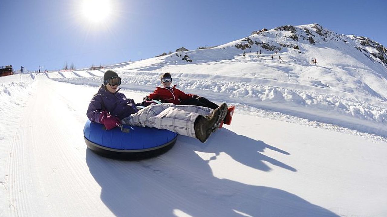 Duas crianças deslizando na neve com boias de tubing em Farellones, uma das atividades mais populares para famílias perto de Santiago.
