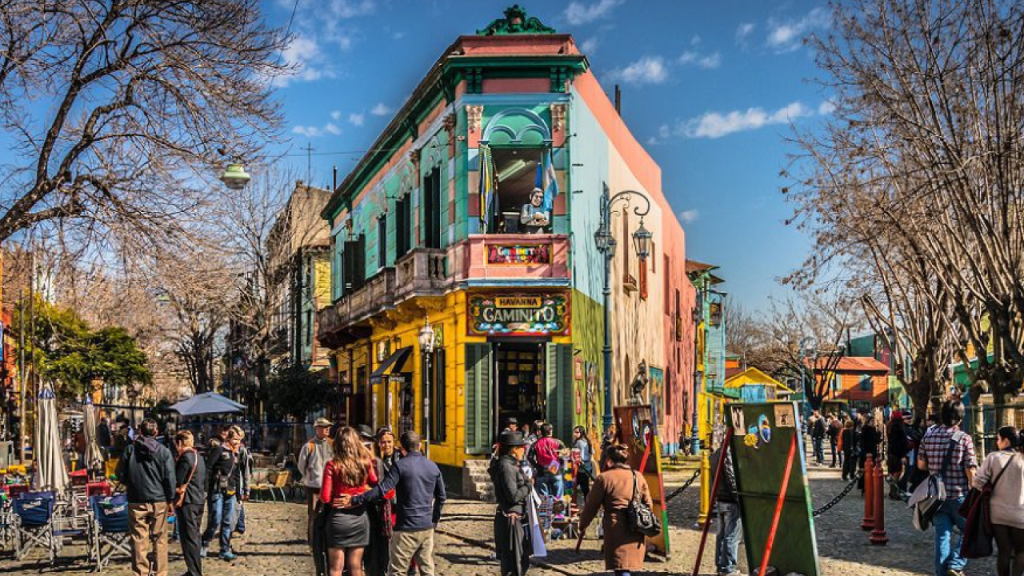Rua Caminito em Buenos Aires, com casas coloridas e turistas caminhando.