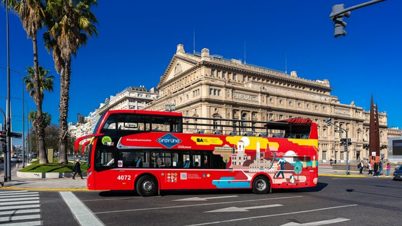 Ônibus vermelho de city tour passando pelo Teatro Colón em Buenos Aires.