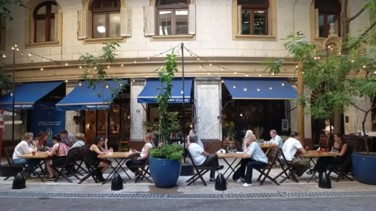 Mesas ao ar livre em restaurante com clientes conversando.