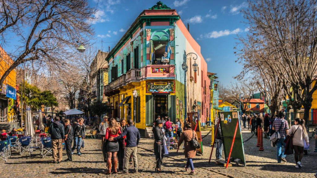 Caminito, em La Boca, sob sol de verão; fachadas coloridas e turistas nas ruas.