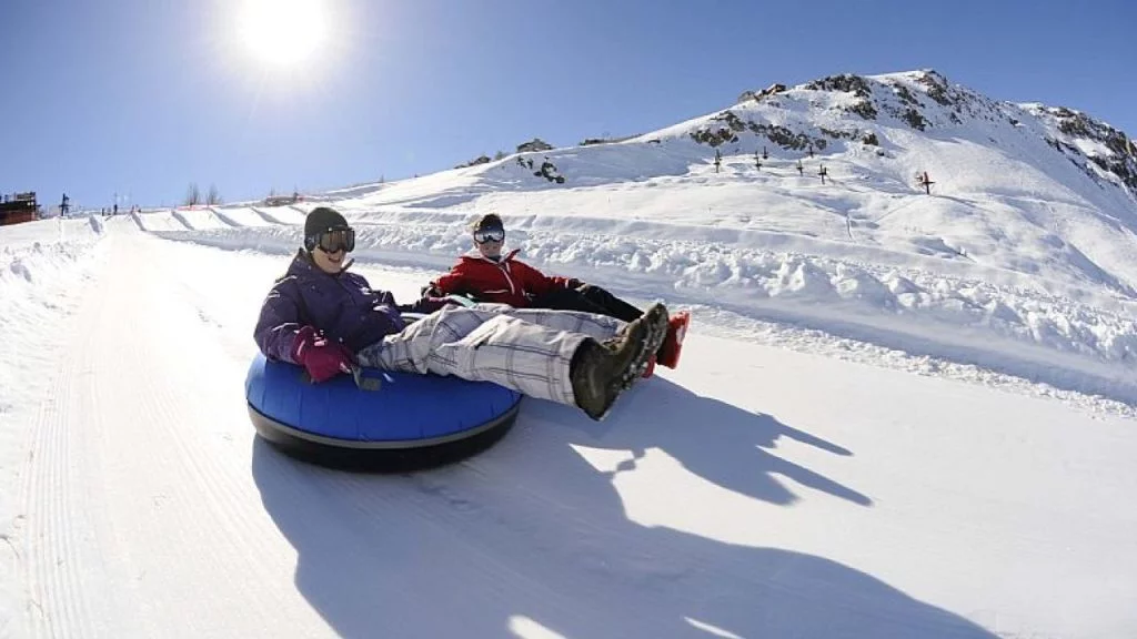 Duas crianças deslizando na neve com boias de tubing em Farellones, uma das atividades mais populares para famílias perto de Santiago.
